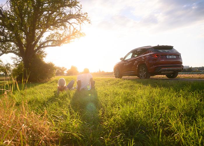 Hyundai Tucson color rojo junto a un árbol al atardecer